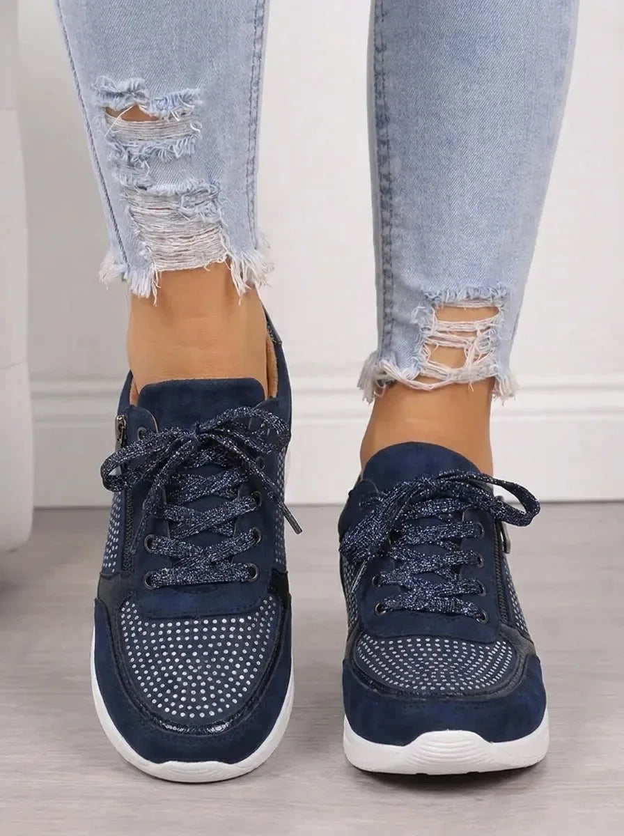 Front view of navy suede trainers with sparkling rhinestone mesh panels and glitter laces, worn with ripped jeans