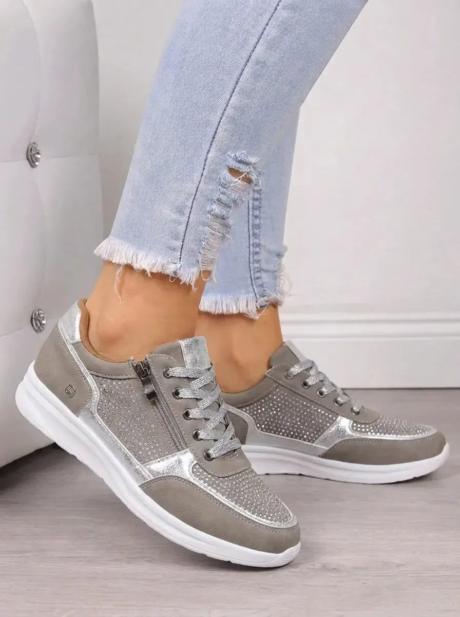 Gold metallic trainers with rhinestone mesh panels, zip side and white wedge sole worn with jeans