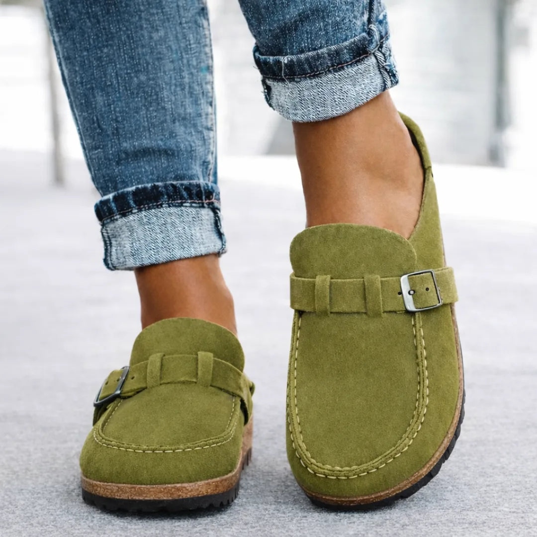 Olive green suede backless loafers with silver buckle strap and contrast stitching, front angle view.