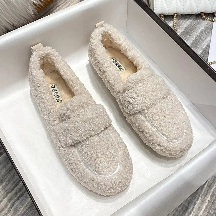 Pair of cream teddy fleece loafers with tonal strap detail displayed inside a white shoebox
