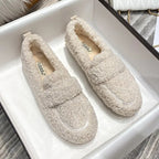 Pair of cream teddy fleece loafers with tonal strap detail displayed inside a white shoebox
