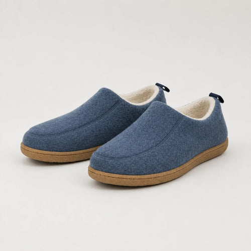Pair of blue wool-felt slipper shoes with tan rubber soles and cream fleece lining, shown at an angle