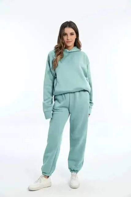 Front view of a woman in a mint green oversized hoodie and matching jogger set styled with white trainers