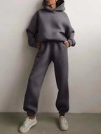 Woman standing in a charcoal grey brushed hoodie and jogger set with drawstring hood and elastic cuffs