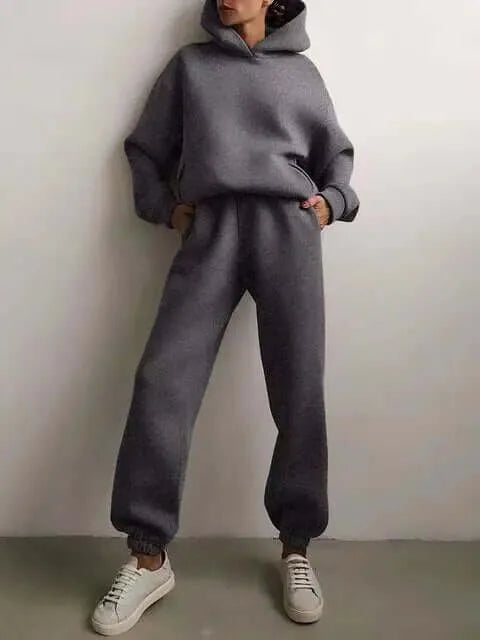 Woman standing in a charcoal grey brushed hoodie and jogger set with drawstring hood and elastic cuffs