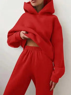 Cropped view of a red oversized hoodie worn with matching high-waisted joggers, hood pulled up