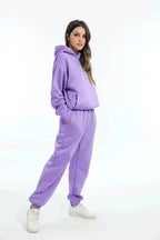 Side profile of a woman in a lilac purple hooded tracksuit with relaxed fit and white trainers