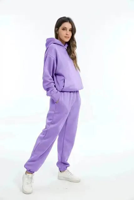 Side profile of a woman in a lilac purple hooded tracksuit with relaxed fit and white trainers