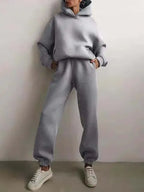 Woman standing in a light grey brushed fleece hoodie and jogger set with an oversized silhouette