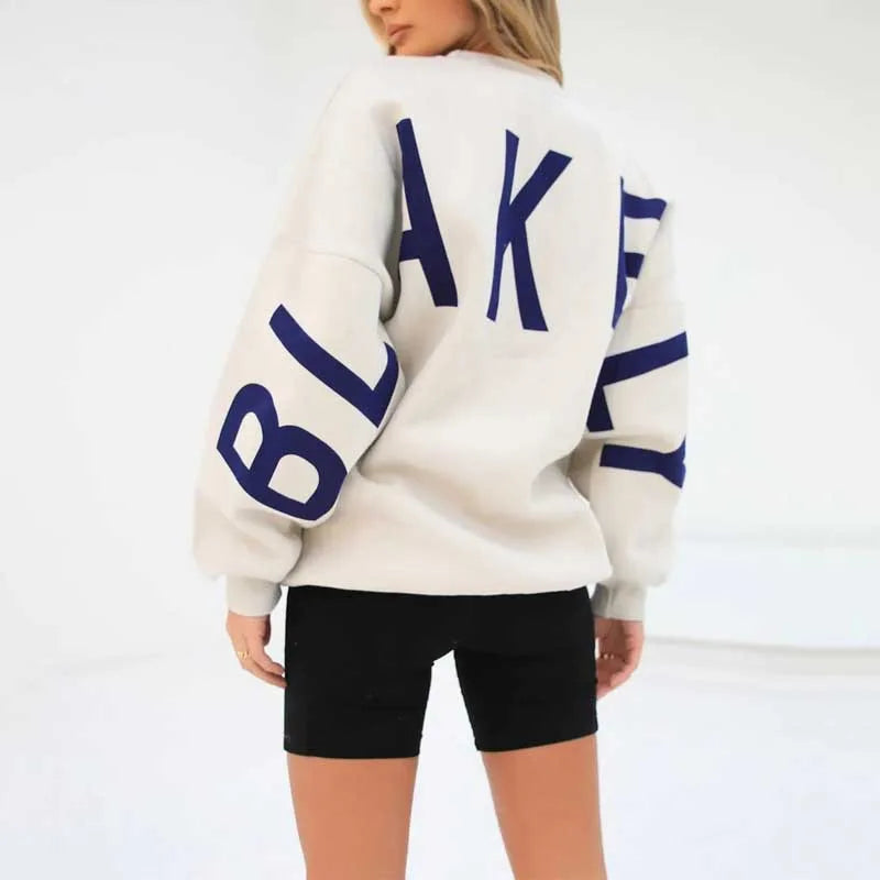 Back view of a cream jumper showing large navy blue letter print spanning the shoulders and sleeves