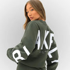 Close-up back view of a khaki green oversized jumper with white lettering print detail