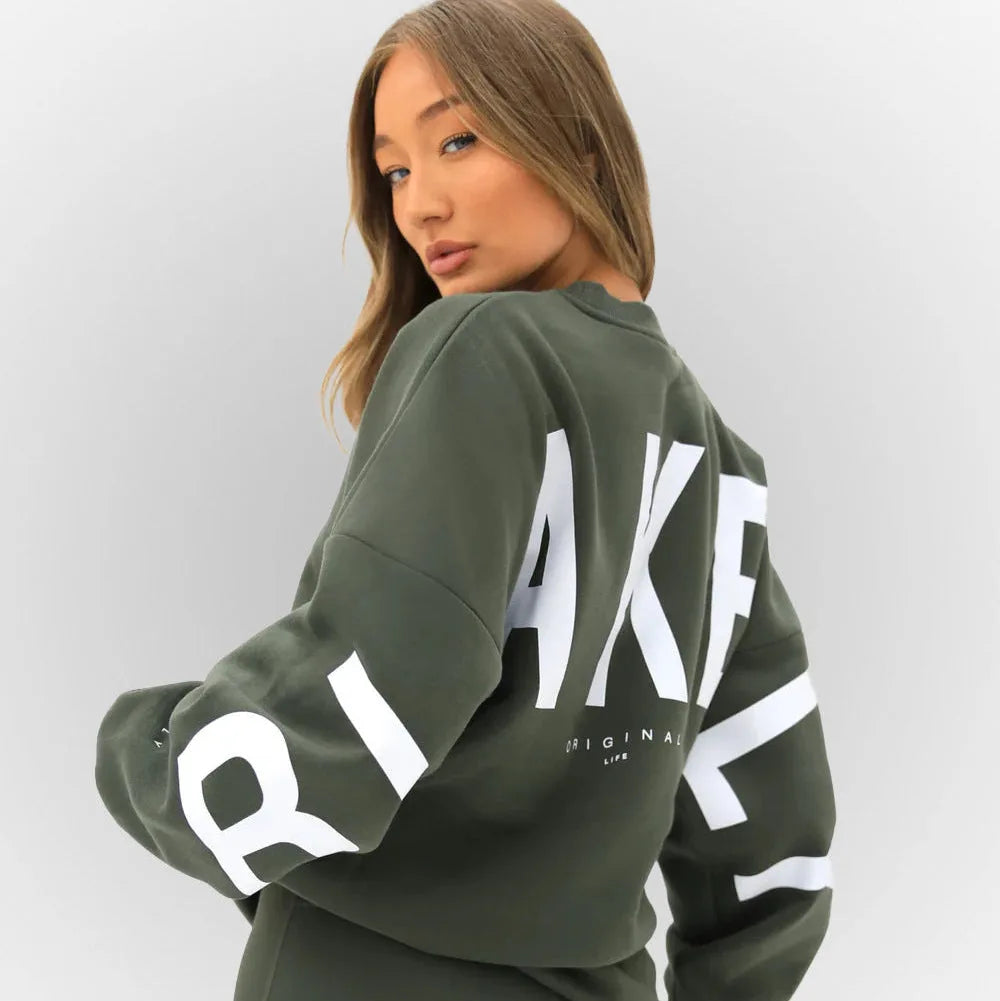 Close-up back view of a khaki green oversized jumper with white lettering print detail