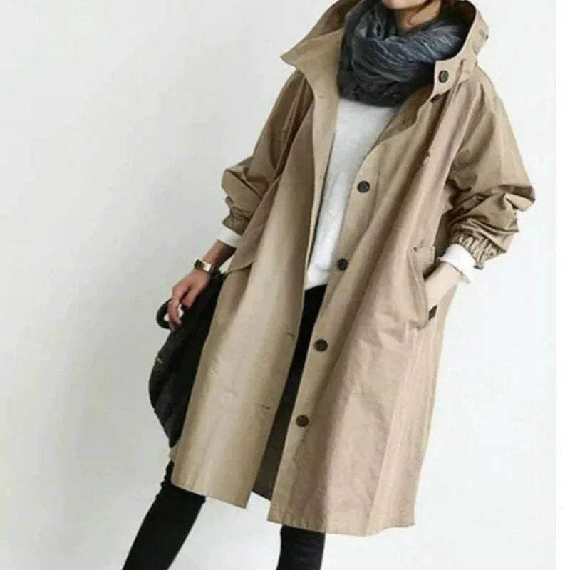 Camel coloured hooded trench coat with button placket and side pockets, worn over black leggings