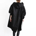 Back view of a black hooded trench coat highlighting the oversized hood and asymmetric hemline