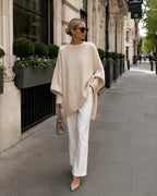 Woman in London wearing an oversized beige knit jumper with ribbed hem over white tailored trousers