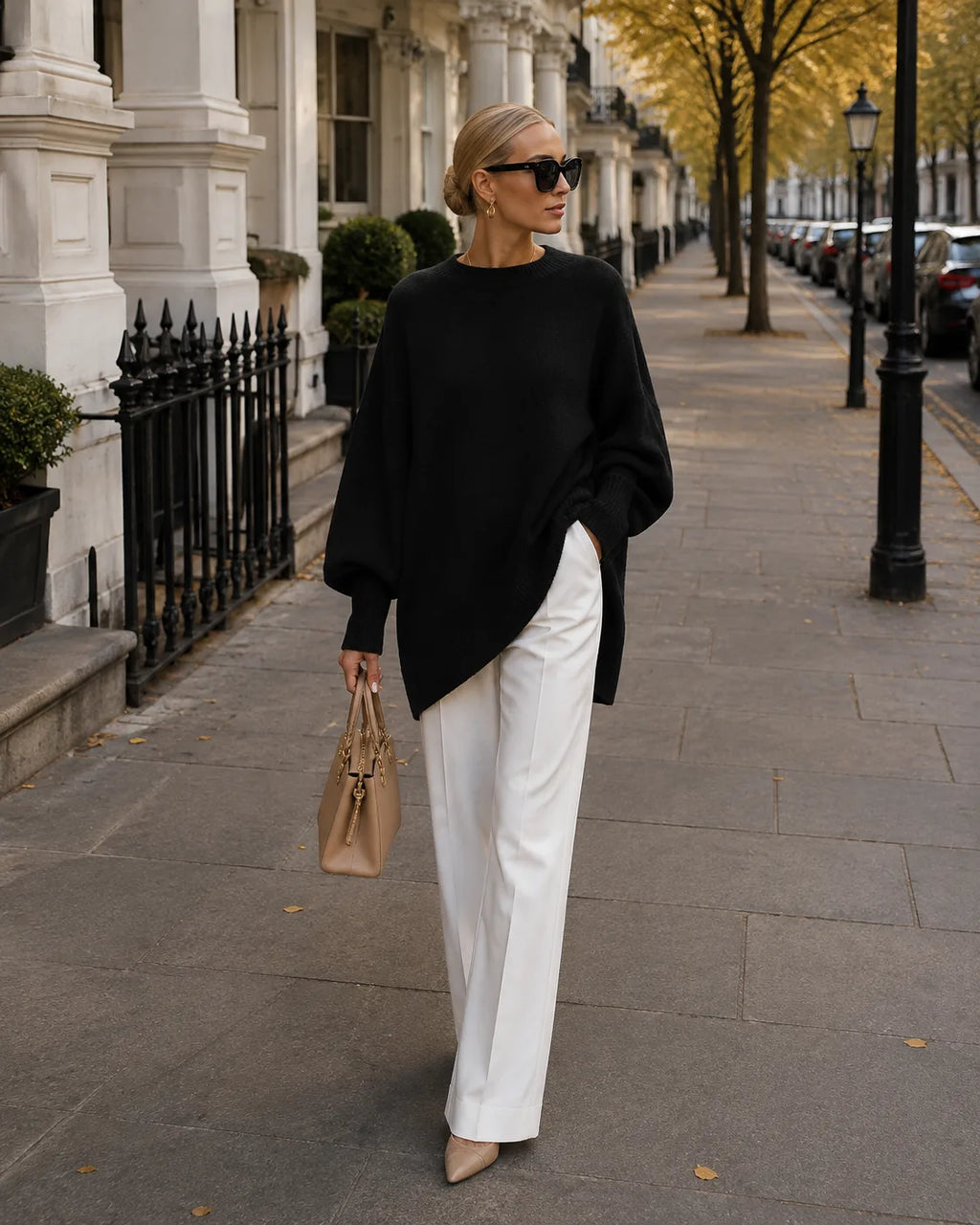 Black oversized jumper with wide sleeves and side split hem worn with white trousers and heels