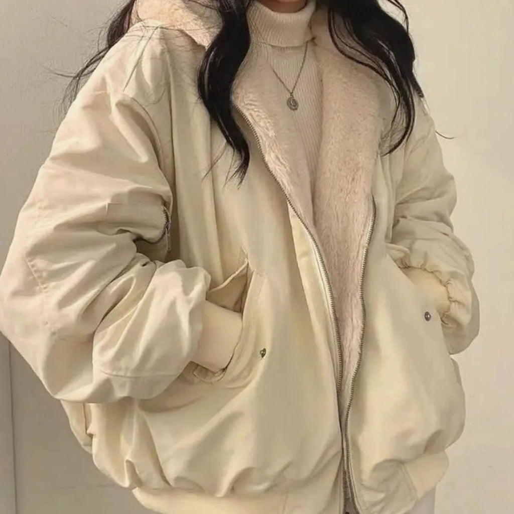 Close-up of a beige double-layered winter jacket with plush teddy fur lining, worn open over a cream polo neck jumper