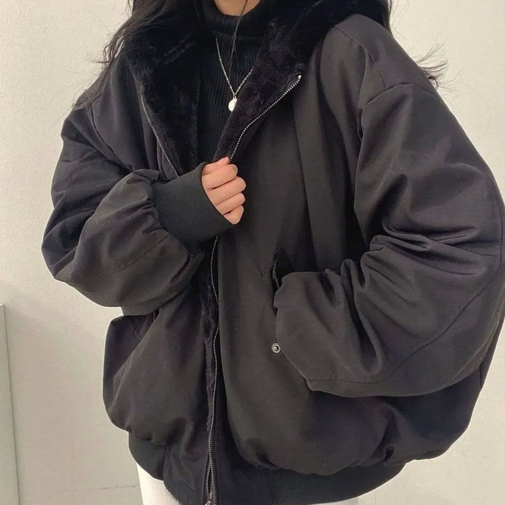 Cropped front view of a black oversized winter jacket with fur-lined hood and zip pocket with popper fastening