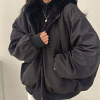 Cropped front view of a black oversized winter jacket with fur-lined hood and zip pocket with popper fastening