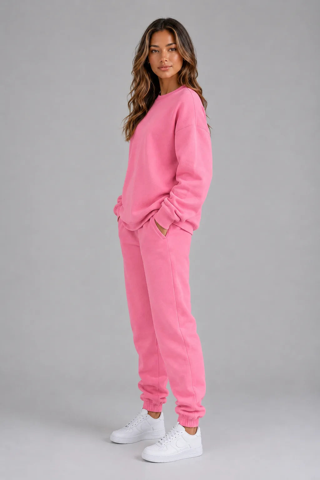 Side profile of the pink sweatshirt and joggers set with hands in pockets, showing the relaxed silhouette