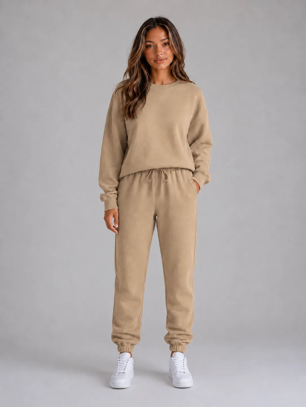Full-length front view of the oversized tracksuit set in a warm beige tone with white trainers