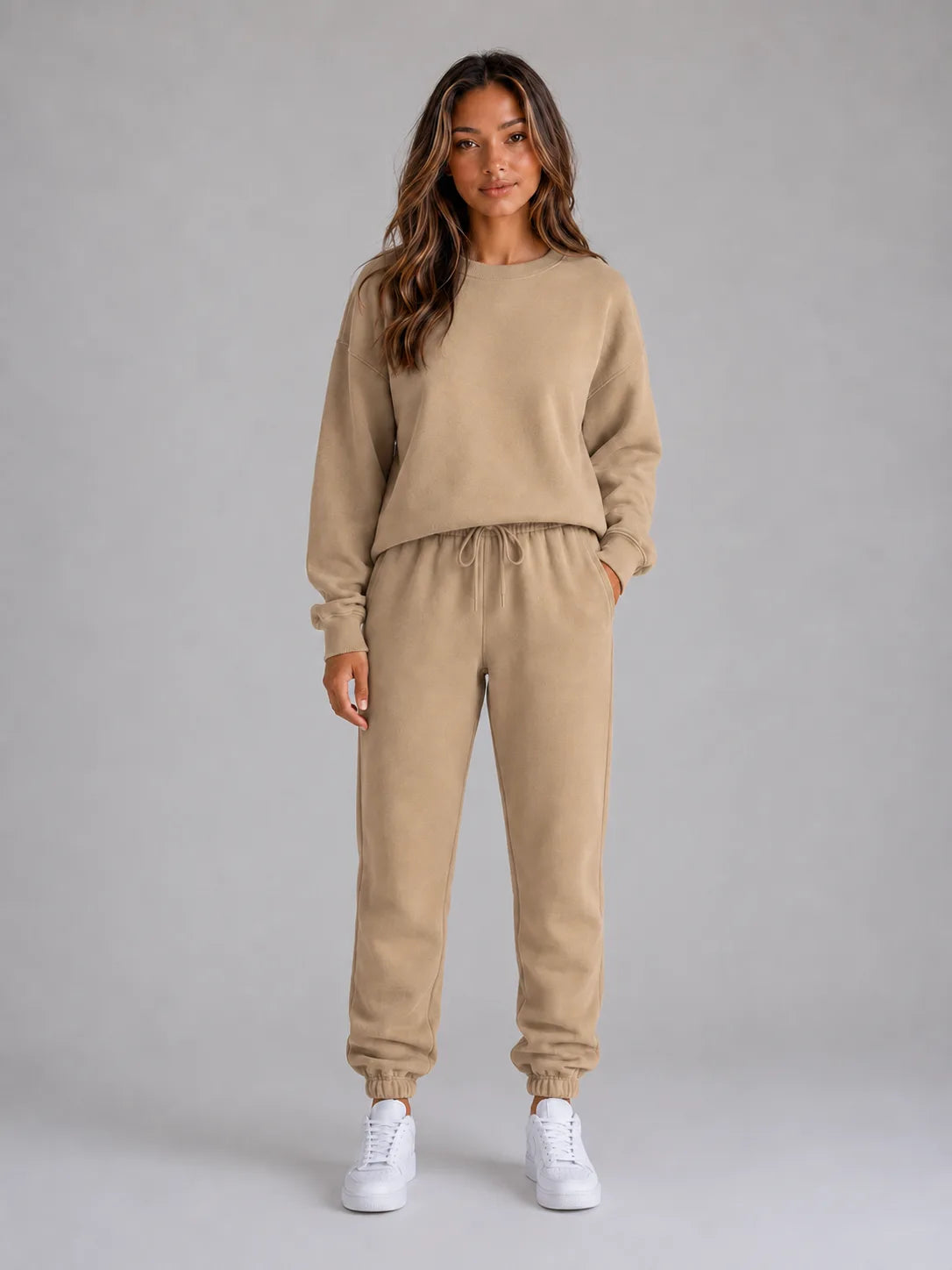 Full-length front view of the oversized tracksuit set in a warm beige tone with white trainers