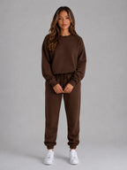 Full-length front view of the oversized tracksuit set in dark brown with white trainers
