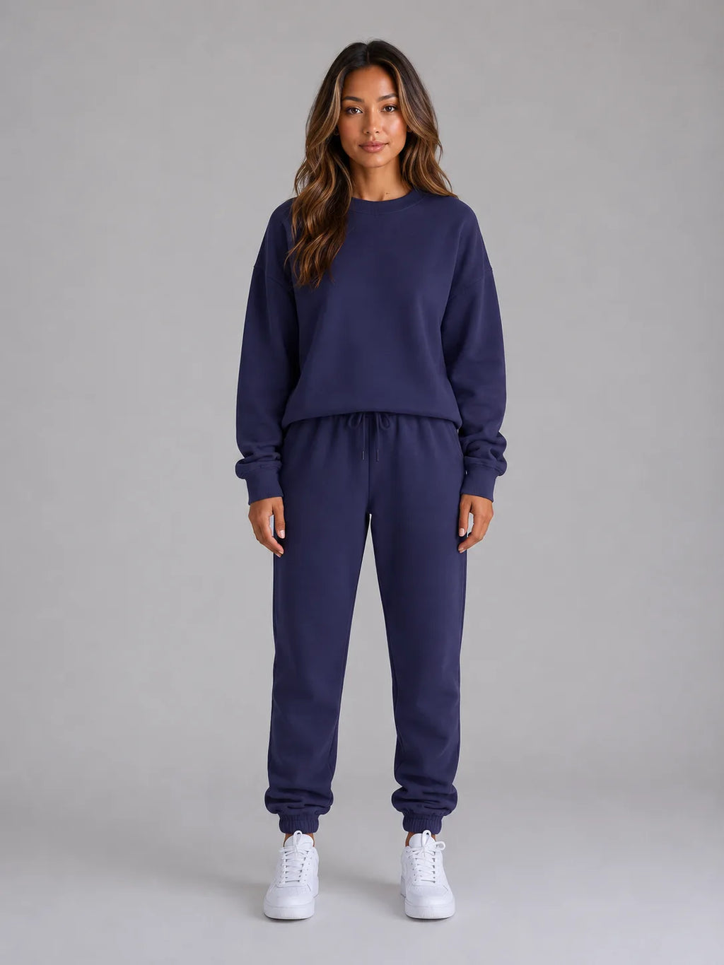 Front view of a woman modelling the oversized sweatshirt and jogger set with hands tucked in the waistband