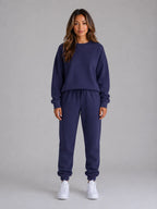 Front view of a woman modelling the oversized sweatshirt and jogger set with hands tucked in the waistband