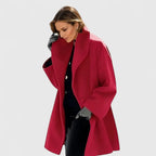 Woman wearing a bright red oversized wool coat with wide shawl collar and dropped shoulders, worn open over black trousers