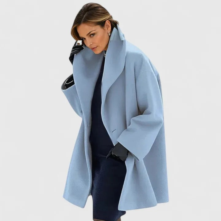 Pale sky blue oversized wool coat with wide collar, shown open over a navy midi dress, three-quarter length sleeves visible