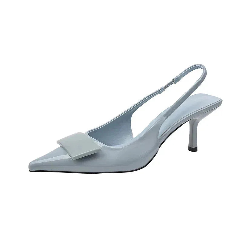 Angled studio shot of a pale blue patent slingback pump with pointed toe and squared buckle accent on a plain background