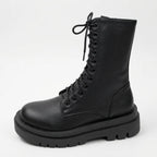 Close-up side view of black combat boot showing lace eyelets, back zip and ridged platform outsole
