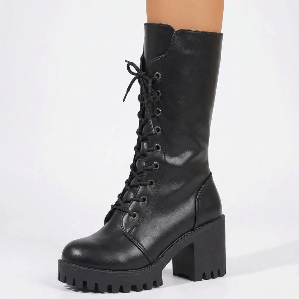 Close-up side view of a single black combat boot showing the lace-up front, eyelets and ridged platform sole