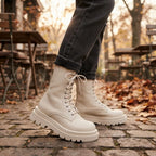Close-up of a person wearing cream lace-up platform combat boots paired with cropped jeans outdoors