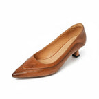 Angled front-side view of brown leather pump highlighting stitched vamp panel and slim heel