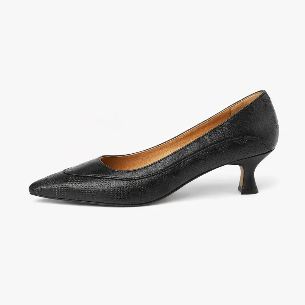 Side profile of black leather kitten heel pump with pointed toe and subtle textured panel detail