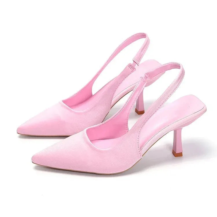 Soft pink satin slingback pumps with pointed toe, shown from the front on a white background