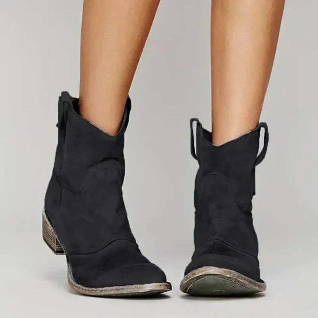 Black suede pointed-toe ankle boots shown from the front with distressed stacked block heel and pull tabs