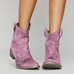 Mauve suede ankle boots with pull-tab detail at the back and low stacked heel, front-facing close up
