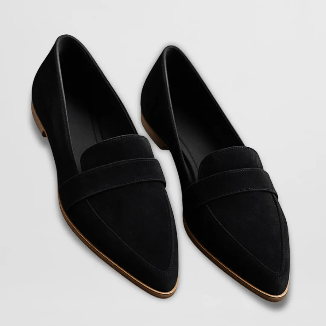 Pair of black suede pointed-toe loafers with penny strap, shown flat lay with tan leather soles visible