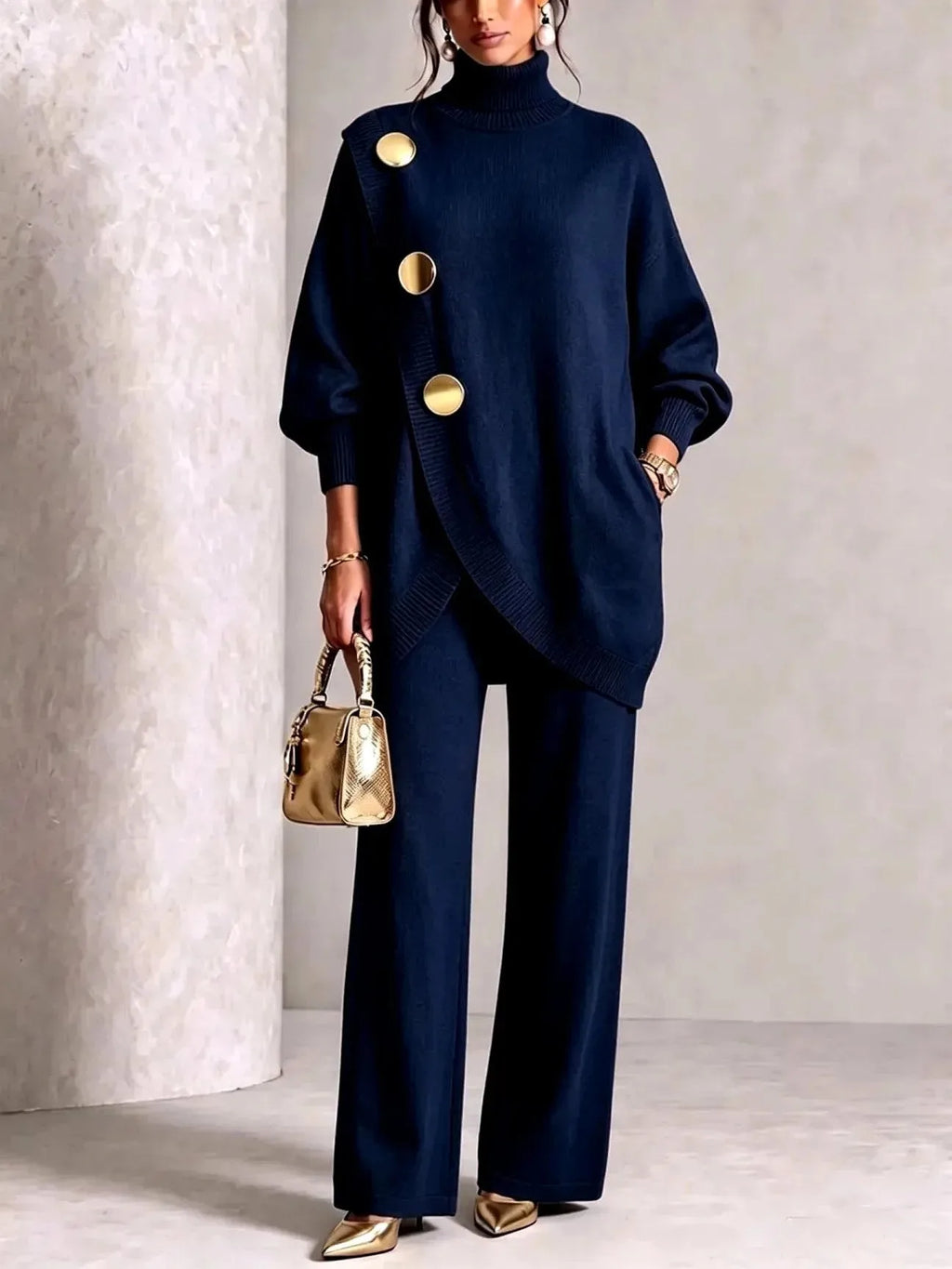 Navy knit tunic and trouser set photographed against a neutral studio backdrop with gold handbag detail