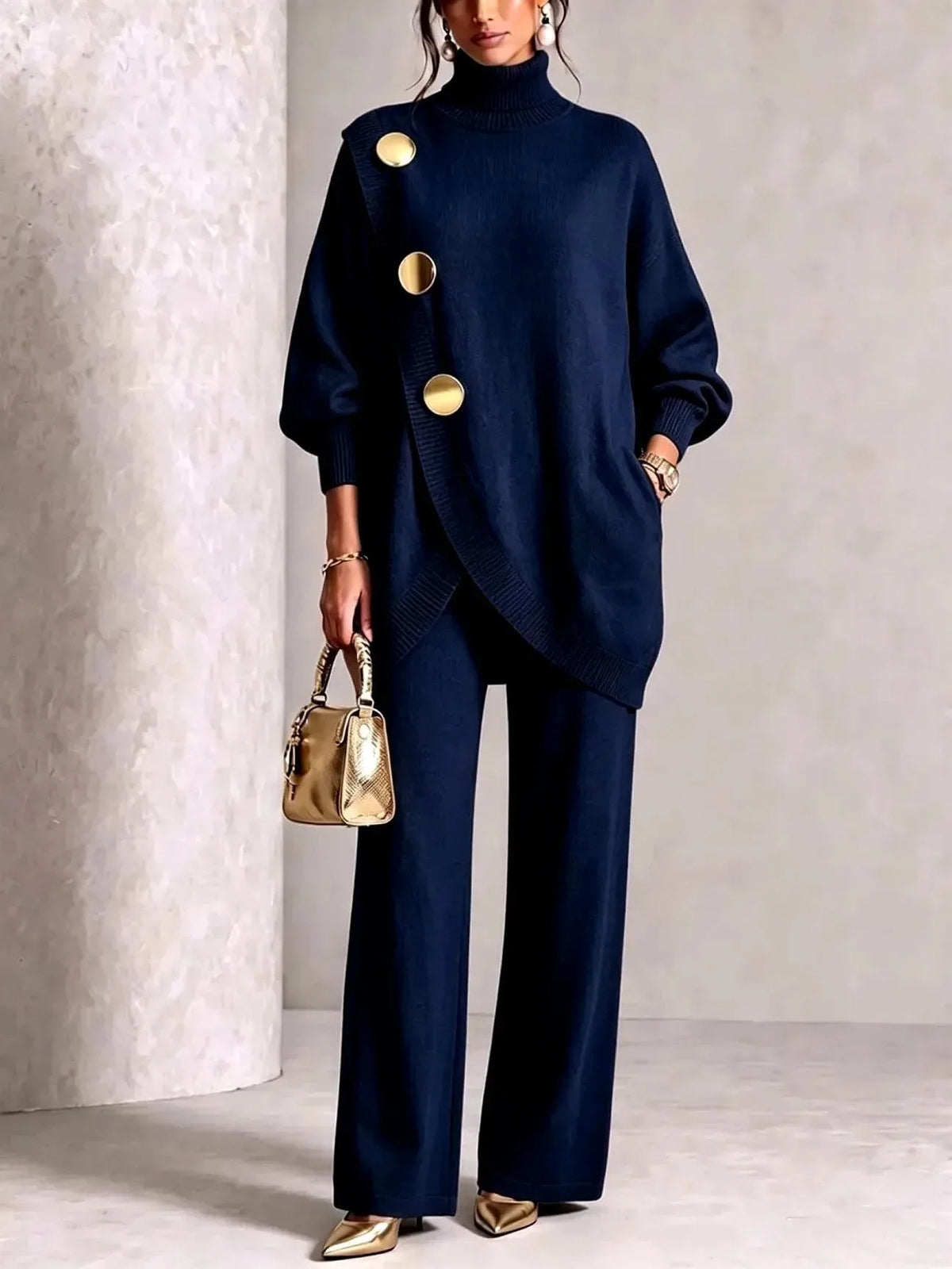 Navy knit tunic and trouser set photographed against a neutral studio backdrop with gold handbag detail