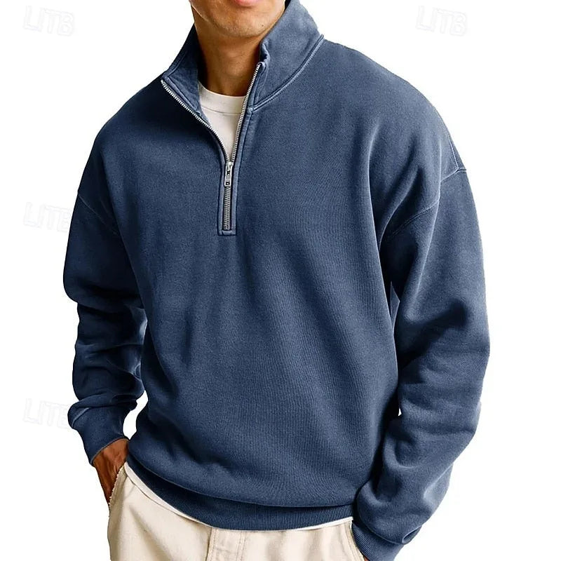 Man wearing a navy blue quarter-zip sweatshirt with stand collar, front angled view showing zip pull detail