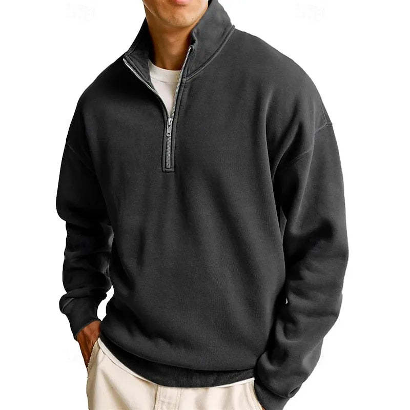 Front view of a brown quarter-zip sweatshirt with hands tucked into cream trouser pockets