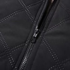 Macro view of the diamond quilting stitch lines and front zip pull on the black shell fabric