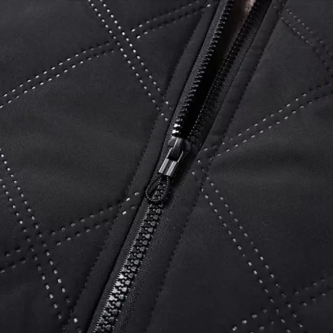 Macro view of the diamond quilting stitch lines and front zip pull on the black shell fabric