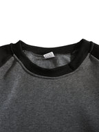Close-up of the ribbed crew neckline and raglan seam detail in black and grey