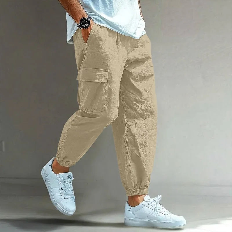 Khaki cargo trousers in a lightweight crinkled fabric, showing the side pocket flap and tapered elastic cuff detail