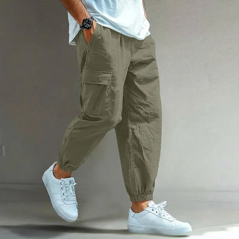 Olive green cargo trousers with elastic waistband and relaxed tapered leg, side profile shot with white trainers